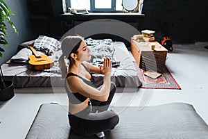 Young caucasian fitness woman meditate, doing yoga indoors at home near the bed. Staying fit and healthy