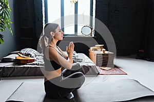 Young caucasian fitness woman meditate, doing yoga indoors at home near the bed. Staying fit and healthy