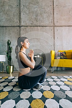 Young caucasian fitness woman meditate, doing yoga indoors at home near the bed. Staying fit and healthy