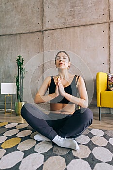 Young caucasian fitness woman meditate, doing yoga indoors at home near the bed. Staying fit and healthy
