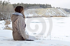 A young Caucasian girl in a brown coat staring into the distance on the horizon line