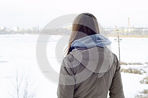 A young Caucasian girl in a brown coat staring into the distance on the horizon line