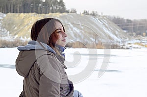 A young Caucasian girl in a brown coat staring into the distance on the horizon line