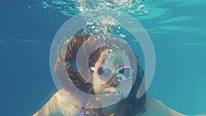 Young Caucasian Girl Diving in Swimming Pool Breathing Out Air Bubbles