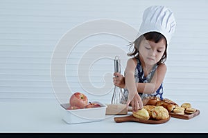 A young Caucasian girl holding whisk pretend to mix bread ingredients