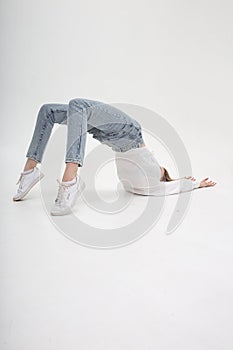 Young caucasian girl lying on floor, lifting her body, stretching on cyclorama