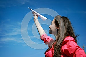 Young caucasian girl with paper plane in the hand