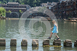 Young Caucasian girl on stepping stones in Fenghuang