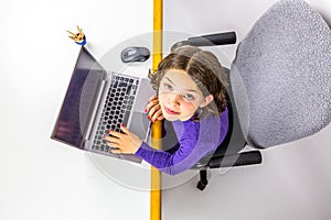 Young Caucasian girl study using laptop looking up. Studio shot from above.