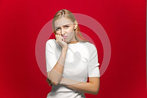 Young caucasian girl suffer toothache, pain from sensitive tooth on red studio background. Dental clinic advertising