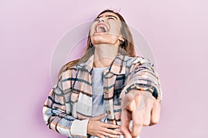 Young caucasian girl wearing casual clothes laughing at you, pointing finger to the camera with hand over body, shame expression