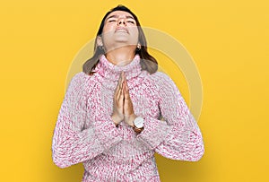 Young caucasian girl wearing wool winter sweater begging and praying with hands together with hope expression on face very