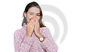 Young caucasian girl wearing wool winter sweater laughing and embarrassed giggle covering mouth with hands, gossip and scandal