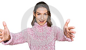 Young caucasian girl wearing wool winter sweater looking at the camera smiling with open arms for hug