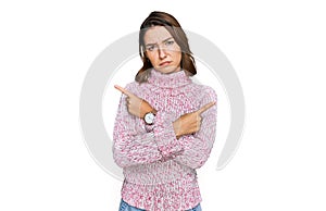 Young caucasian girl wearing wool winter sweater pointing to both sides with fingers, different direction disagree