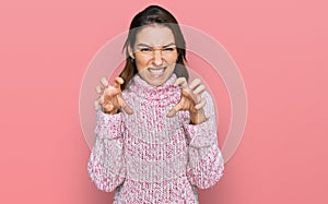 Young caucasian girl wearing wool winter sweater smiling funny doing claw gesture as cat, aggressive and sexy expression