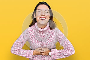 Young caucasian girl wearing wool winter sweater smiling and laughing hard out loud because funny crazy joke with hands on body
