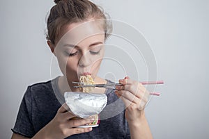 Young caucasian girl woman eating instant noodles ramen with chopsticks