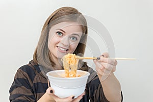 Young caucasian girl woman eating instant noodles ramen with chopsticks