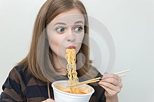 Young caucasian girl woman eating instant noodles ramen with chopsticks