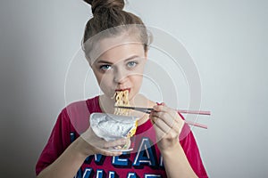 Young caucasian girl woman eating instant noodles ramen with chopsticks