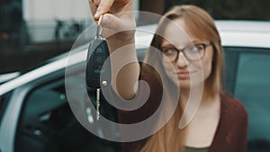 Young caucasian happy woman in front of the new car and holding keys