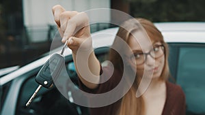 Young caucasian happy woman in front of the new car and holding keys