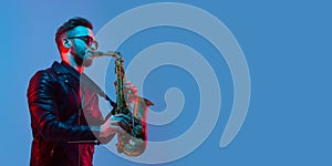 Young caucasian jazz musician playing the saxophone in neon light, flyer photo