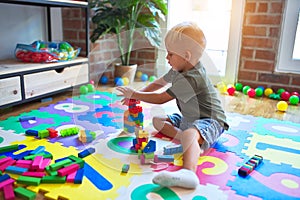 Young caucasian kid playing at kindergarten with toys. Preschooler boy happy at playroom