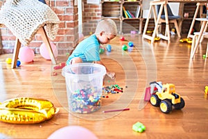 Young caucasian kid playing at kindergarten with toys. Preschooler boy happy at playroom