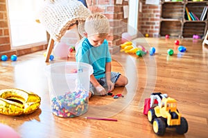 Young caucasian kid playing at kindergarten with toys. Preschooler boy happy at playroom