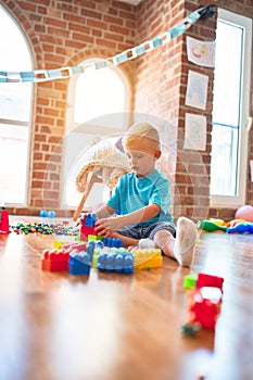 Young caucasian kid playing at kindergarten with toys. Preschooler boy happy at playroom