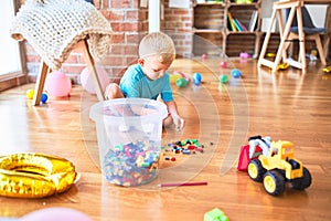 Young caucasian kid playing at kindergarten with toys. Preschooler boy happy at playroom