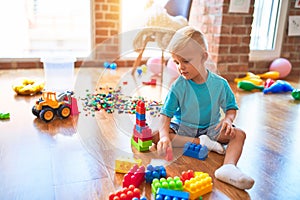 Young caucasian kid playing at kindergarten with toys. Preschooler boy happy at playroom