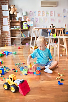 Young caucasian kid playing at kindergarten with toys. Preschooler boy happy at playroom