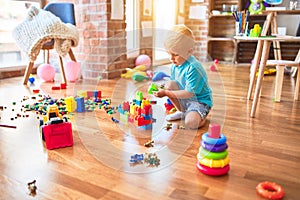 Young caucasian kid playing at kindergarten with toys. Preschooler boy happy at playroom