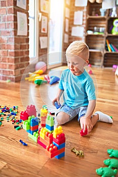 Young caucasian kid playing at kindergarten with toys. Preschooler boy happy at playroom