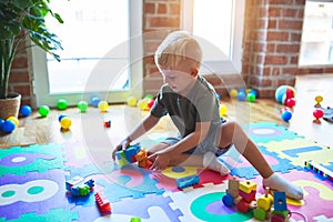 Young caucasian kid playing at kindergarten with toys. Preschooler boy happy at playroom