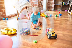 Young caucasian kid playing at kindergarten with toys. Preschooler boy happy at playroom