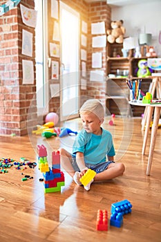 Young caucasian kid playing at kindergarten with toys. Preschooler boy happy at playroom