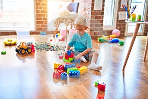 Young caucasian kid playing at kindergarten with toys. Preschooler boy happy at playroom