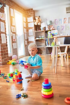 Young caucasian kid playing at kindergarten with toys. Preschooler boy happy at playroom