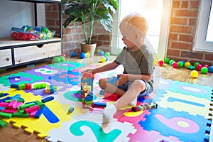 Young caucasian kid playing at kindergarten with toys. Preschooler boy happy at playroom