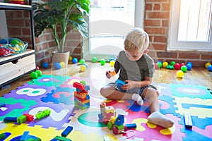 Young caucasian kid playing at kindergarten with toys. Preschooler boy happy at playroom