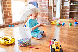 Young caucasian kid playing at kindergarten with toys. Preschooler boy happy at playroom