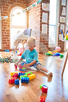 Young caucasian kid playing at kindergarten with toys. Preschooler boy happy at playroom