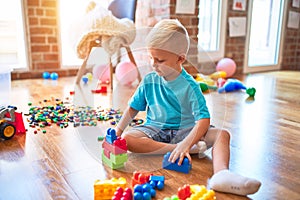 Young caucasian kid playing at kindergarten with toys. Preschooler boy happy at playroom