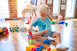 Young caucasian kid playing at kindergarten with toys. Preschooler boy happy at playroom