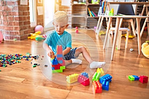 Young caucasian kid playing at kindergarten with toys. Preschooler boy happy at playroom