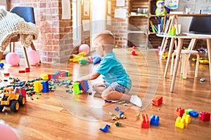 Young caucasian kid playing at kindergarten with toys. Preschooler boy happy at playroom